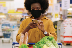 African-American woman shopping for groceries while using her cell phone